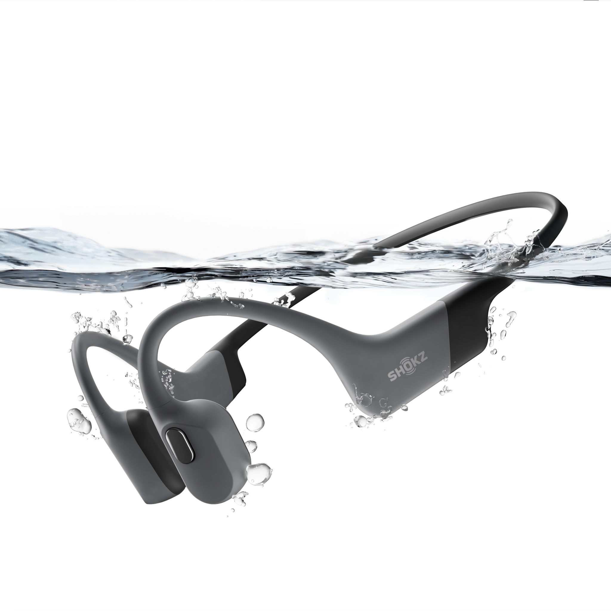 Grey Shokz OpenSwim Pro waterproof bone conduction headphones partially submerged in water with splashing bubbles.